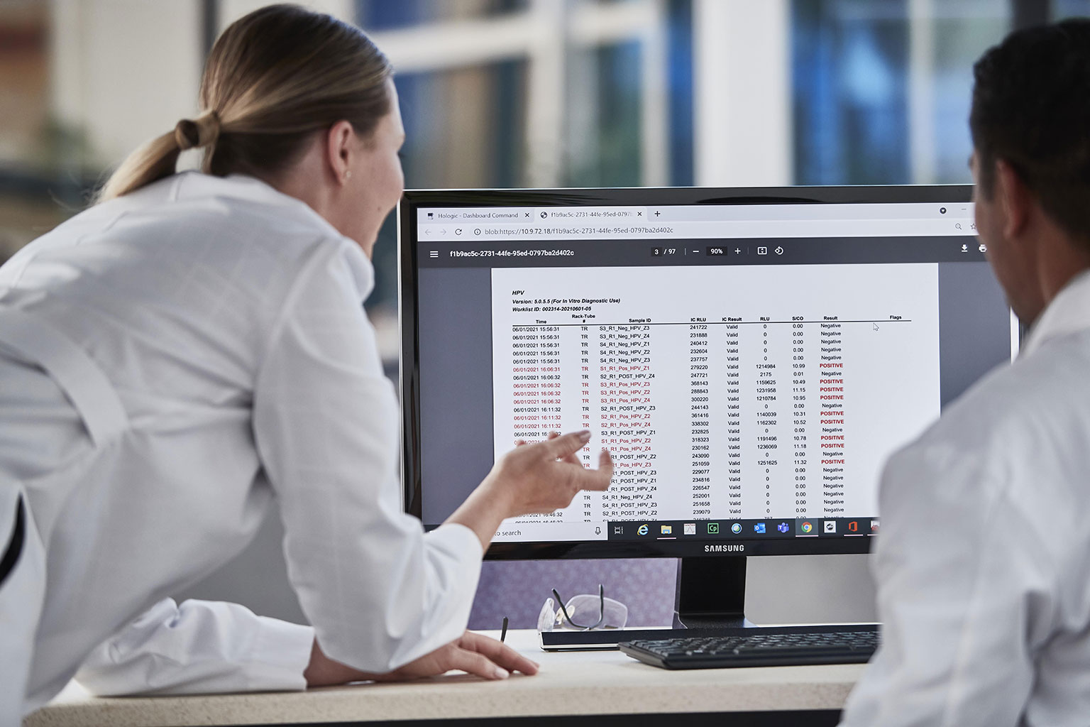 Lab technicians looking at data on a monitor in a lab setting.