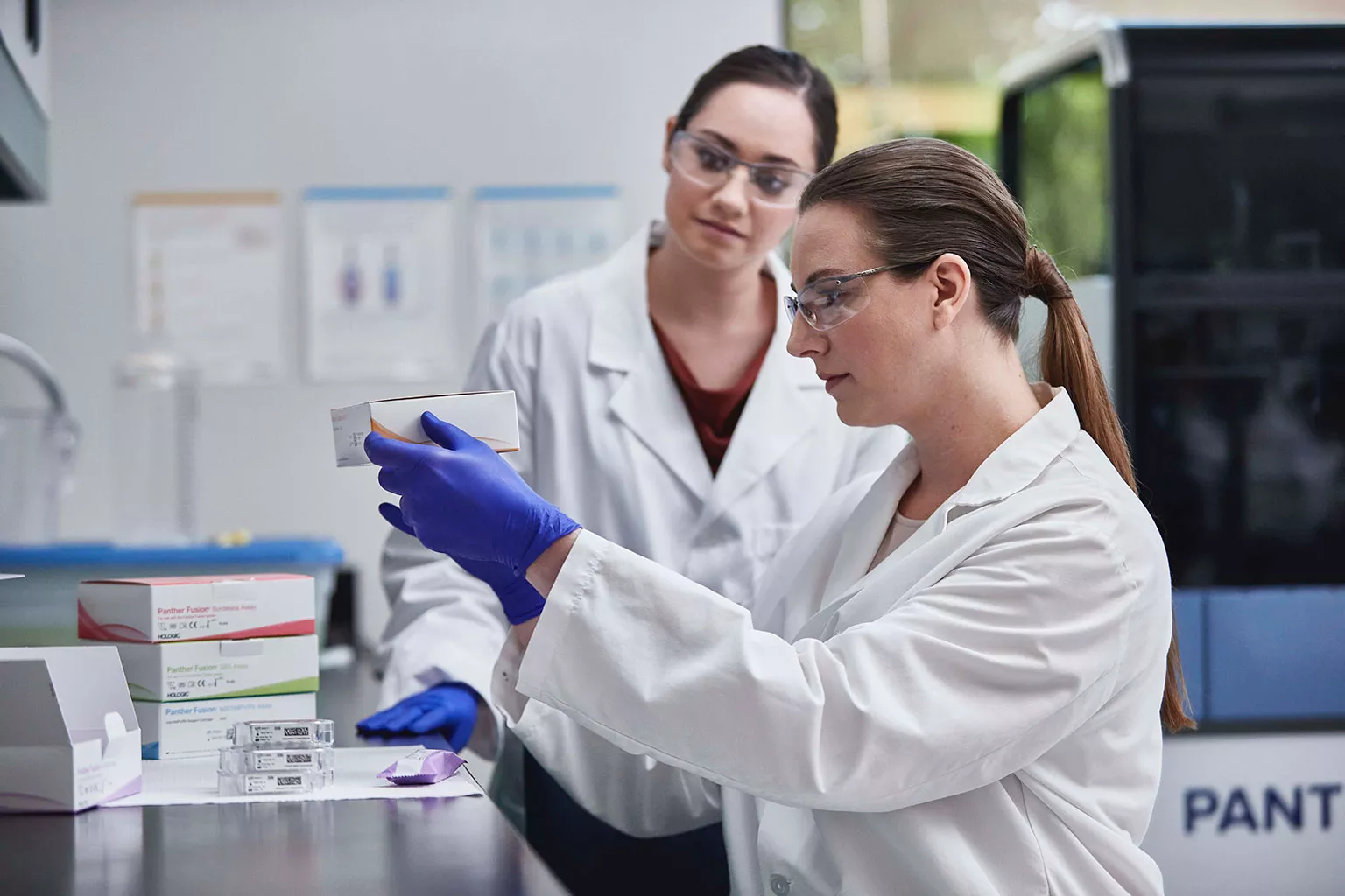 Lab technicians holding assay box in lab setting.