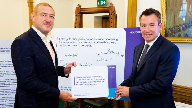Two man in suits hold pledge board together